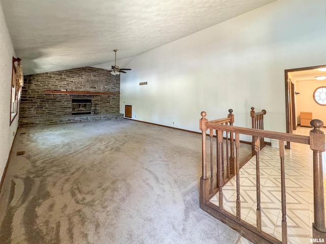 carpeted living room with vaulted ceiling, ceiling fan, and a stone fireplace