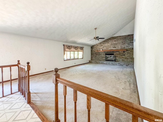 unfurnished living room featuring lofted ceiling, a fireplace, ceiling fan, and light colored carpet