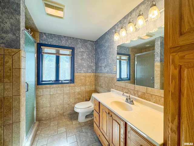 bathroom with tile walls, walk in shower, vanity, and toilet