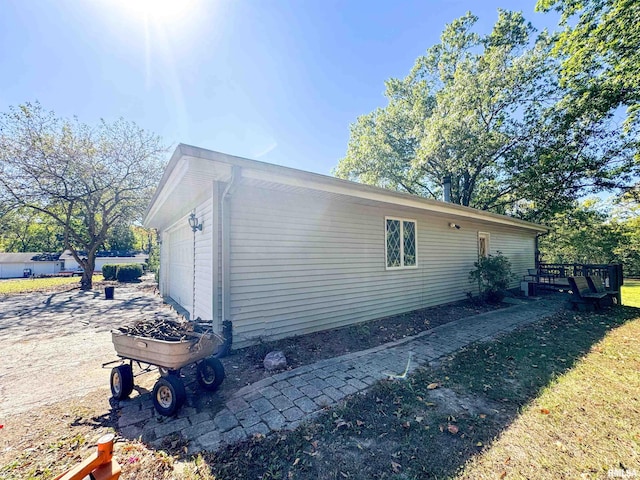 view of home's exterior featuring a lawn, a deck, and a garage