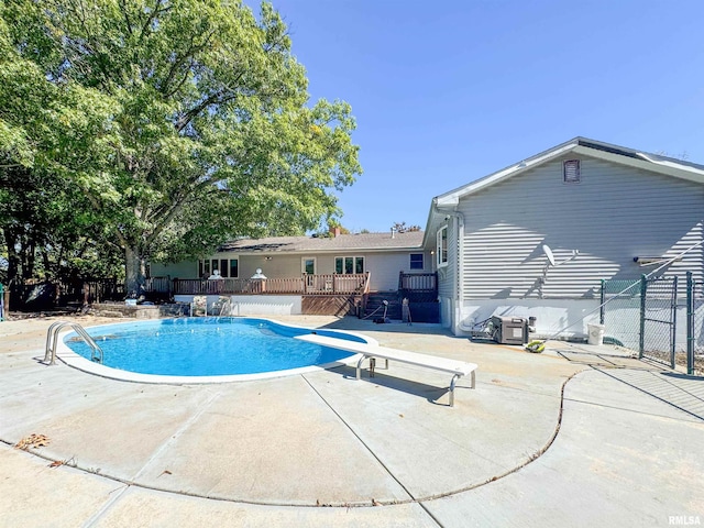 view of pool with a diving board, a wooden deck, and a patio area