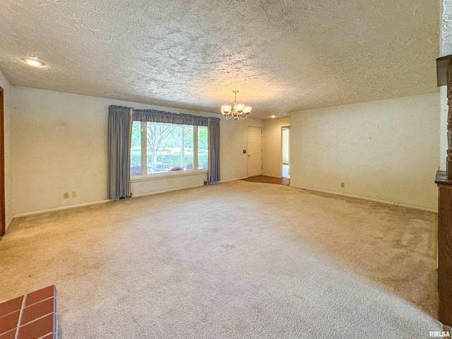 unfurnished room featuring an inviting chandelier, a textured ceiling, and carpet flooring