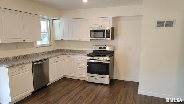 kitchen with appliances with stainless steel finishes, dark hardwood / wood-style floors, and white cabinets