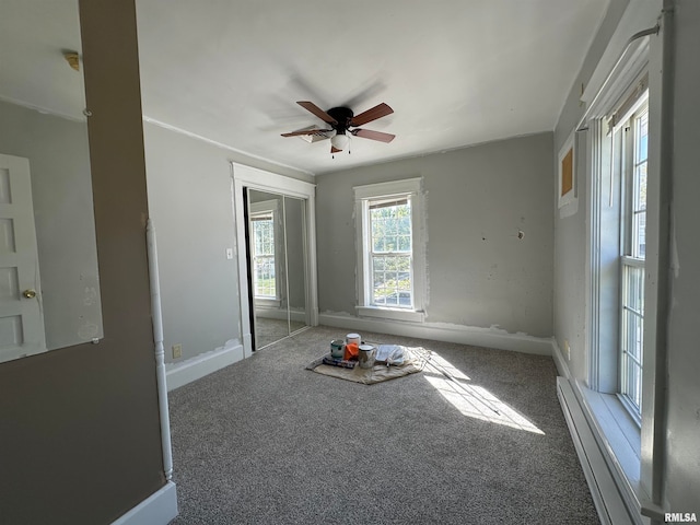 carpeted empty room featuring a baseboard heating unit and ceiling fan