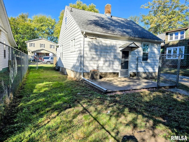 rear view of property featuring a lawn, central AC, and a patio