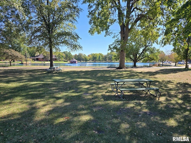 view of property's community with a water view and a lawn