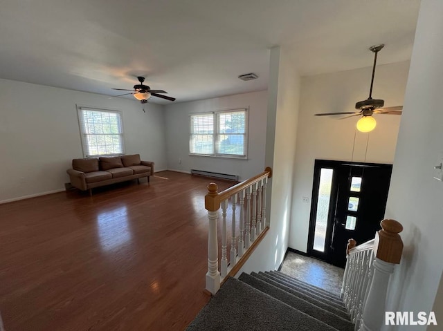 foyer entrance with baseboard heating, dark wood-type flooring, and ceiling fan