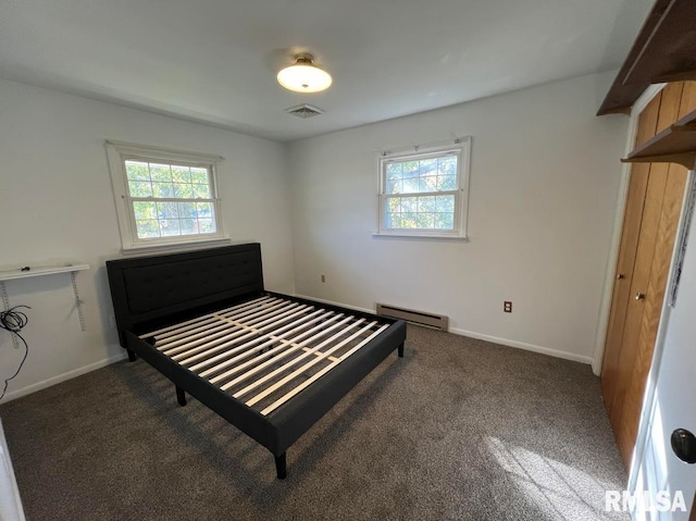 carpeted bedroom featuring multiple windows, a baseboard heating unit, and a closet