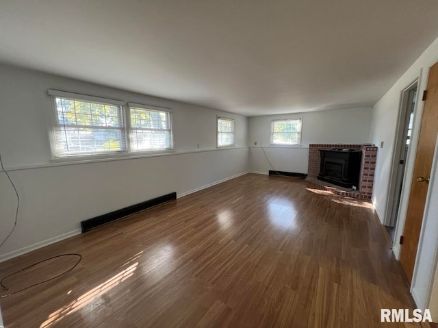 unfurnished living room with a baseboard radiator, a brick fireplace, and dark hardwood / wood-style floors