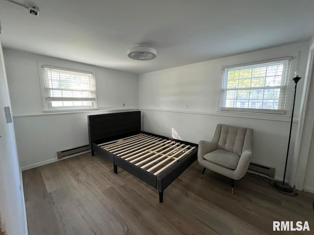 bedroom with a baseboard radiator, wood-type flooring, and multiple windows