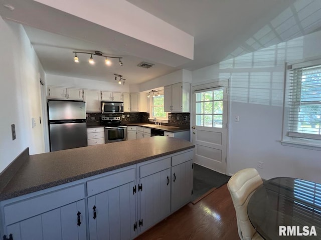 kitchen featuring appliances with stainless steel finishes, white cabinetry, tasteful backsplash, dark hardwood / wood-style flooring, and sink