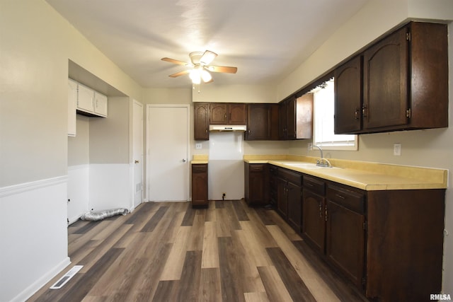 kitchen with dark brown cabinets, dark hardwood / wood-style flooring, ceiling fan, and sink