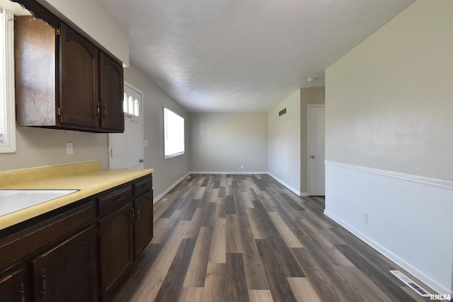 kitchen with dark brown cabinets, dark wood-type flooring, and sink