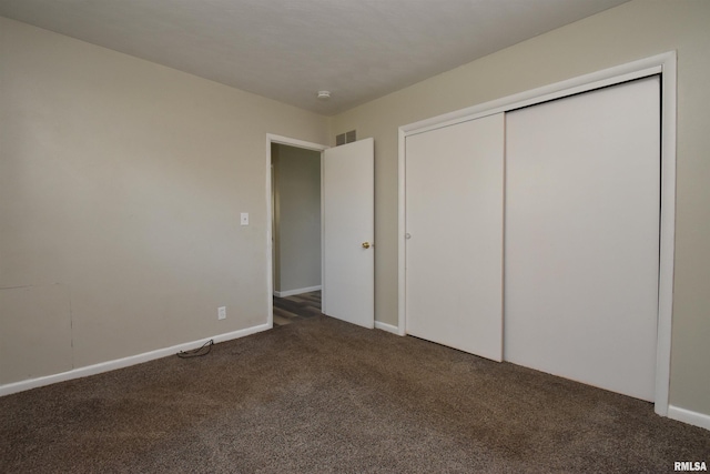 unfurnished bedroom featuring dark colored carpet and a closet