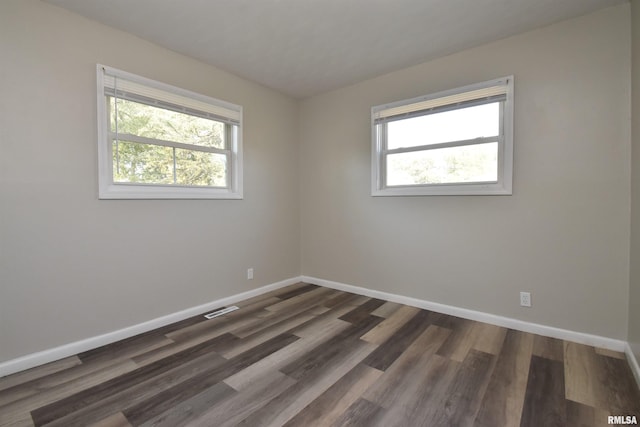 empty room with dark hardwood / wood-style flooring and a healthy amount of sunlight