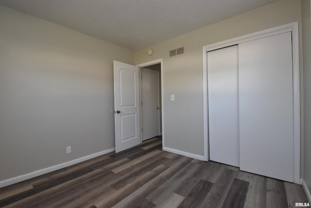 unfurnished bedroom featuring dark hardwood / wood-style flooring and a closet