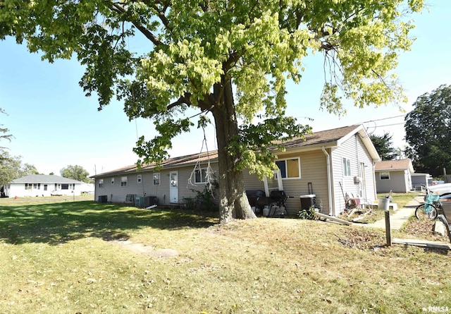 rear view of property featuring a yard and cooling unit