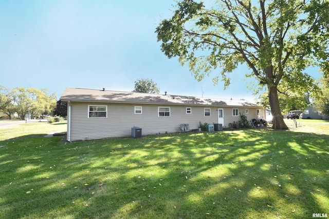 rear view of house featuring a lawn and central air condition unit