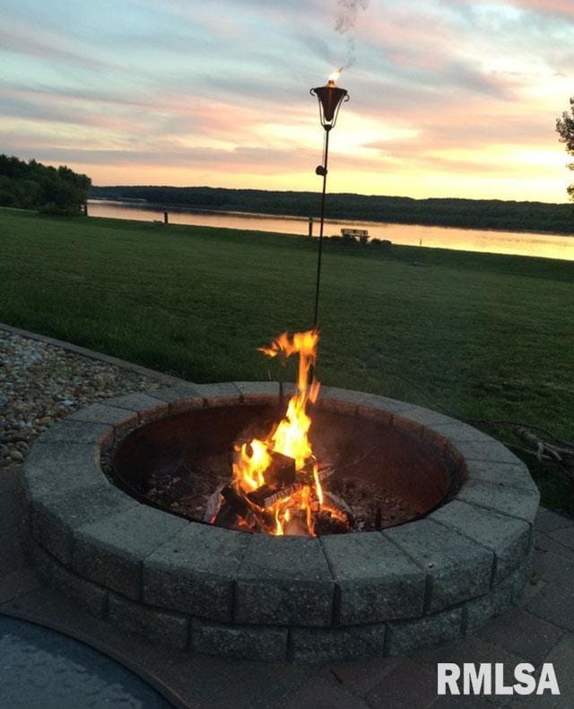 yard at dusk featuring a water view and an outdoor fire pit