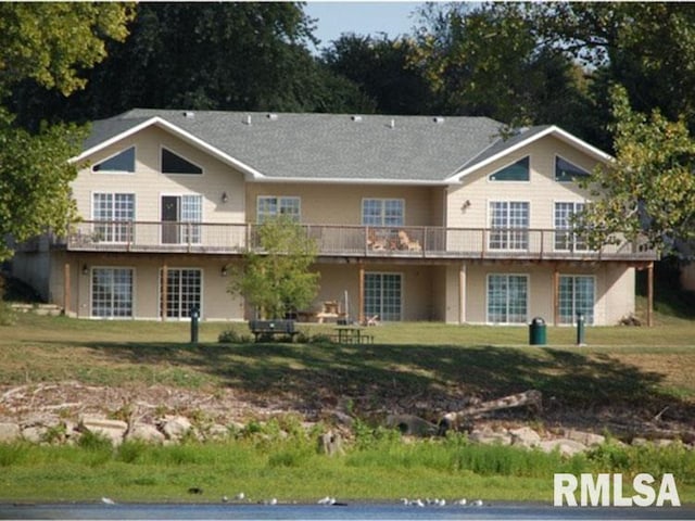 back of property with a lawn and a balcony