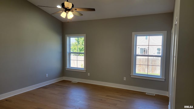 empty room with vaulted ceiling, a wealth of natural light, ceiling fan, and hardwood / wood-style flooring