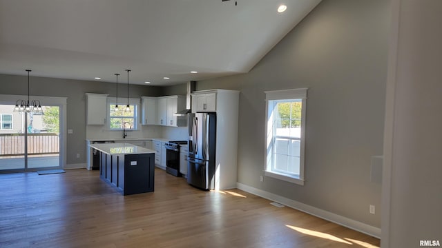 kitchen featuring pendant lighting, white cabinets, plenty of natural light, a kitchen island, and stainless steel appliances