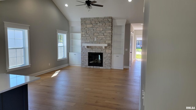 unfurnished living room featuring light hardwood / wood-style floors, high vaulted ceiling, ceiling fan, and a fireplace