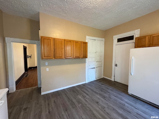 kitchen with white refrigerator, dark wood-type flooring, and a textured ceiling