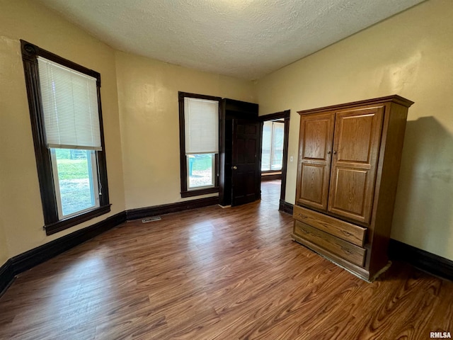 unfurnished bedroom with dark hardwood / wood-style floors and a textured ceiling