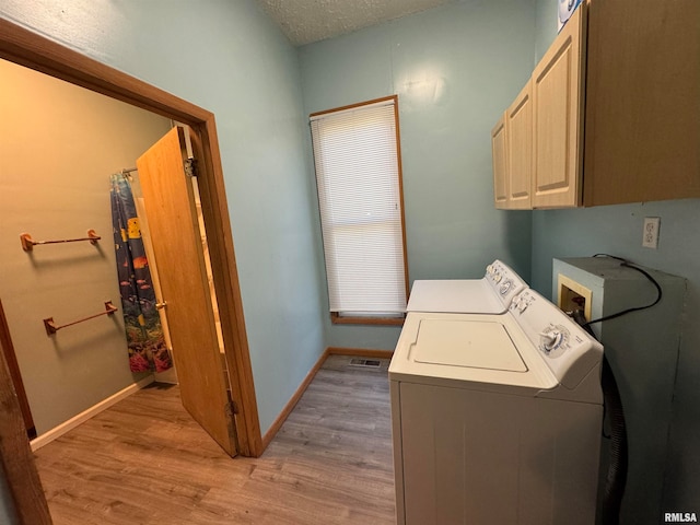 washroom featuring washer and clothes dryer, cabinets, light wood-type flooring, and a textured ceiling