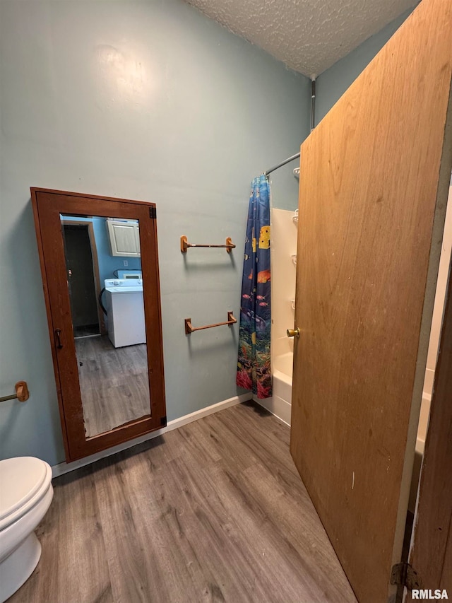 bathroom featuring hardwood / wood-style floors, a textured ceiling, shower / tub combo, washer / dryer, and toilet