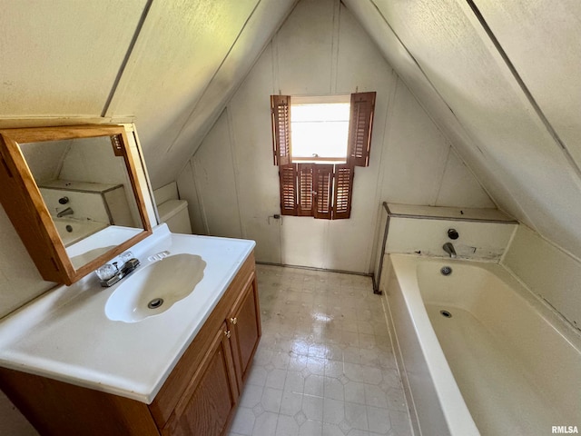 bathroom with a bathtub, vanity, toilet, and vaulted ceiling