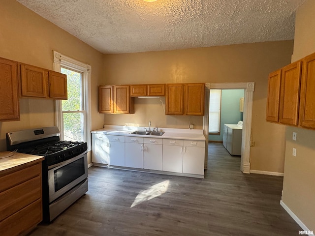 kitchen featuring sink, a textured ceiling, stainless steel gas stove, dark wood-type flooring, and separate washer and dryer