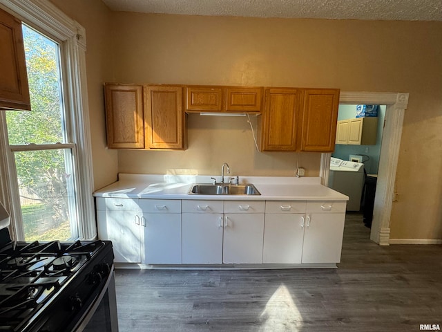 kitchen featuring sink, gas range, white cabinetry, washer / clothes dryer, and dark hardwood / wood-style flooring