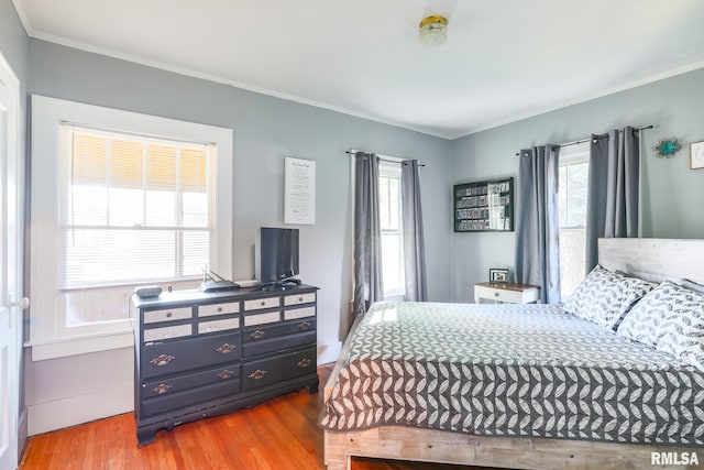 bedroom featuring light hardwood / wood-style flooring, crown molding, and multiple windows