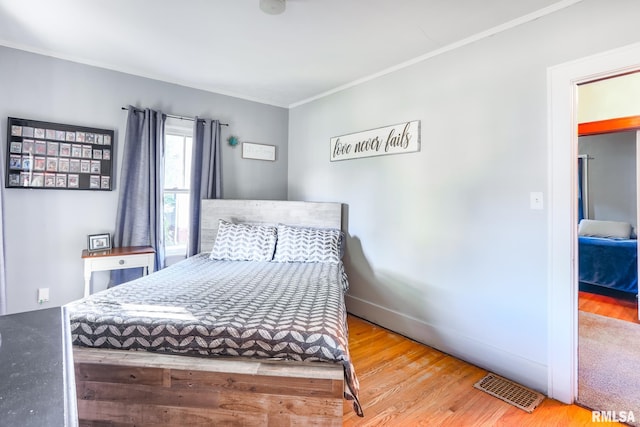 bedroom with ornamental molding and hardwood / wood-style floors