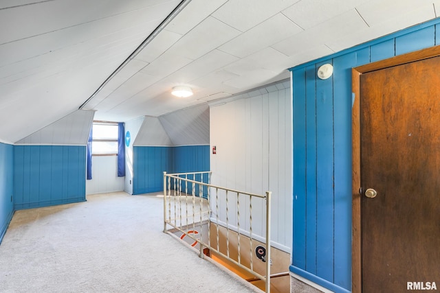 bonus room with wood walls, vaulted ceiling, and carpet