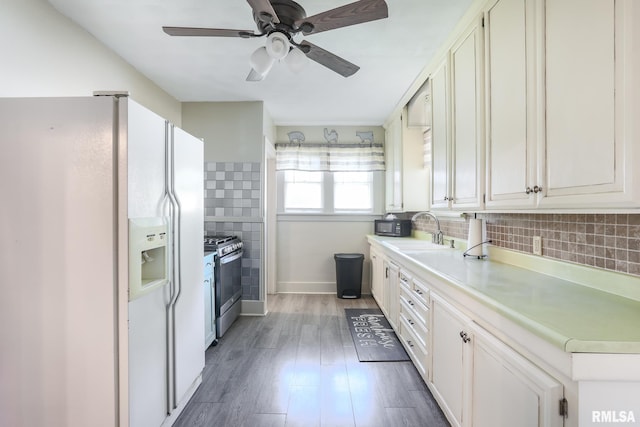 kitchen with sink, white cabinetry, dark hardwood / wood-style floors, white fridge with ice dispenser, and stainless steel range with gas cooktop