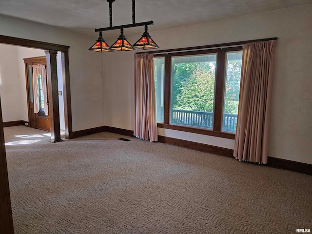 unfurnished room featuring ornate columns and carpet flooring