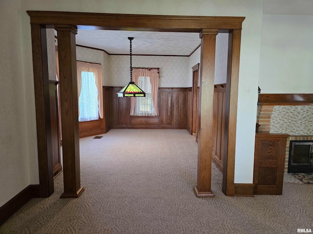 unfurnished dining area featuring wood walls, crown molding, and carpet flooring