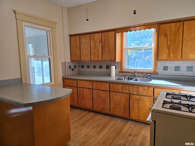 kitchen with light wood-type flooring, plenty of natural light, white range with gas cooktop, and decorative backsplash