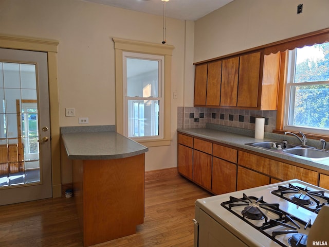 kitchen with a kitchen island, hardwood / wood-style floors, white range with gas stovetop, sink, and decorative backsplash