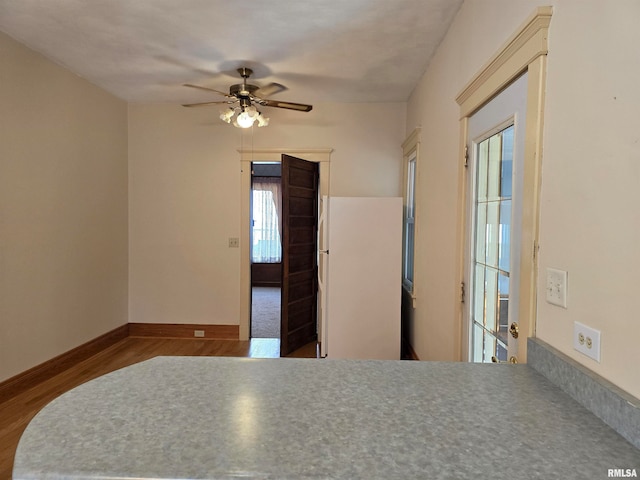 unfurnished bedroom with ceiling fan, white fridge, and hardwood / wood-style flooring