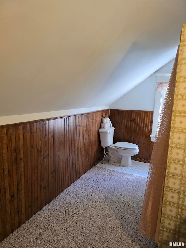 bathroom with lofted ceiling, wood walls, and toilet