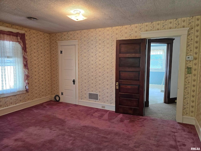 carpeted empty room featuring a textured ceiling