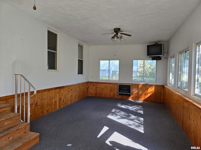 unfurnished sunroom featuring plenty of natural light, heating unit, and ceiling fan