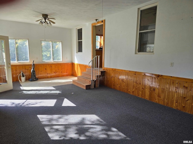 unfurnished room featuring ceiling fan, wooden walls, and carpet