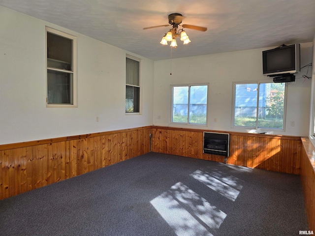 spare room with carpet floors, a textured ceiling, wooden walls, and ceiling fan