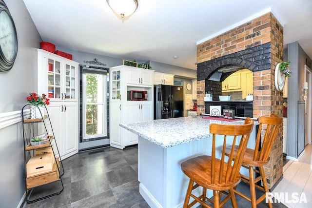 kitchen with black appliances, a kitchen breakfast bar, and white cabinets