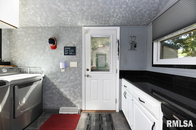 laundry area with dark tile patterned floors, cabinets, and separate washer and dryer